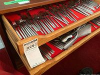 Open drawer with multiple rows of Obelisk stainless steel flatware