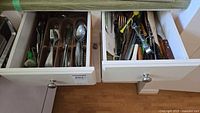 Two open drawers with flatware tray and utensil drawer