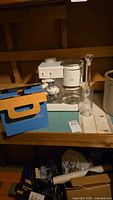 Krups machine, CorningWare box, decanter on shelf