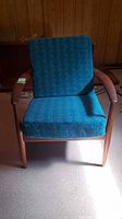 Front view of teak armchair with teal cushions