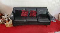 front view of black leather couch with four pillows