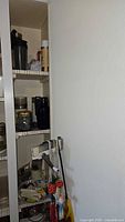 Pantry shelves showing pasta maker clamp, drink containers, mixing bowl, bag clips and other items