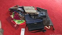 Pile showing majority of bags including navy crossbody, brown pouch, pink and green pouches