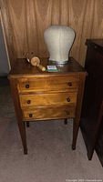 Full view of wooden sewing cabinet with mannequin head and wig stand on top