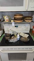 Overall lot on stovetop showing baskets, teapot, slicer, flatware, napkin rings, shakers