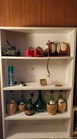 Full shelf view with toy tank, wooden clogs, canteens, spray can, jets, clock, bottles