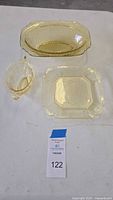 Image of three amber Depression glass pieces including an elongated oval bowl, a rectangular dish, and a handled oval dish, all featuring embossed scroll decoration.