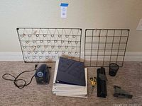 Office supply items arranged on floor: 2 wire racks, electric pencil sharpener, hole puncher, stapler, small pen holder, scissors, and 4 binders.