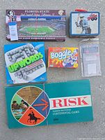 Overview of all items in the lot showing puzzle, games, and lunchbox on concrete