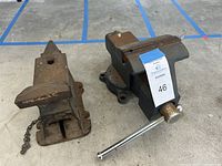 Two vices side by side on concrete floor, one newer Craftsman vise and one older incomplete vise