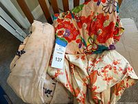 Three kimono dresses stacked showcasing varying floral patterns and colors, with a lot tag visible indicating lot 137.