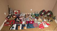 Wide view showing all items spread on floor arranged neatly: wreaths, napkins, tree decorations, figurines, trays, linens, tins, gift bags, and frames.