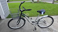 Full side view of green and silver Rico Cruz CALOI bicycle showing frame, basket, handlebars, wheels, pedals, and seat.