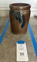 Front view of the brown stoneware butter churning crock showing handpainted dark blue decoration.