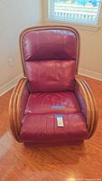 Front view of the burgundy leather rattan rocking recliner chair showing padded seat, backrest, and curved rattan armrests.