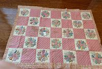 Full view of vintage handmade patchwork quilt laid flat on floor showing pink and floral patchwork design with floral border