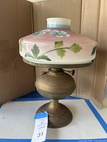 Full view of vintage oil lamp with floral painted glass shade and brass base showing decorative design.
