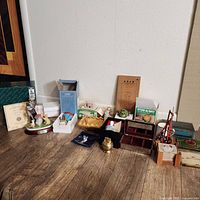 Overview of various small collectible and decorative items including ceramic figurine, tins, and small boxes arranged on the floor.