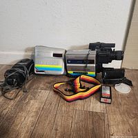 Full view of camcorder with case, charger, battery, wrist strap and accessories on wooden floor