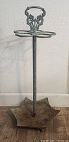 Full view of the vintage cast iron umbrella stand showing decorative handle and circular sections for holding umbrellas.