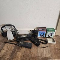 Photo showing all items spread on floor including Suntone headphone radio box, two boxed headphones, mobile phones, and a small white device.