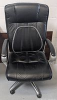 Front view of black leather office chair with mesh lumbar support attached to backrest, padded seat, and armrests.