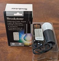 Photo of product box, rope light and remote in clear packaging on wood background.