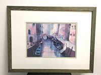 Full view of framed watercolor painting showing Venice canal scene with gondolas and arched bridge, in muted blues, purples, and pinks.