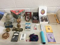 Overview of lot showing multiple items on white table including pottery jar, puzzles, brass pieces, toys, gifts, and novelty items