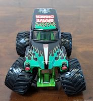 Front angle showing black and green paint with flame graphics, red headlights and oversized BKT tires.