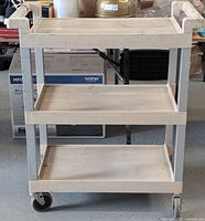 Front view of Rubbermaid Tuffmade utility cart showing three trays and caster wheels.