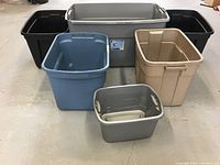 Photo showing all seven plastic storage bins in different colors and sizes arranged on the ground