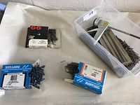 Photo showing boxes of various nails including Stelwire and Claus brand, and a plastic container with loose nails and caulking gun.
