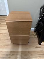 Front view of the 2-drawer filing cabinet showing closed drawers and light oak wood veneer finish.