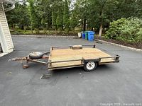 Front-side view showing mesh deck, side rails, tongue and spare tire on deck