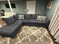 Front view of the sectional sofa showing left-hand chaise, three-seat configuration, and decorative pillows