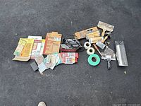 Overview of power sander, sanding blocks, drywall knives, tape rolls and corner trowel laid out on black surface