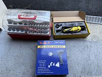 Wide angle photo showing the heat gun box along with the open rotary tool kit and its large bit socket set in a transparent case.