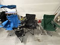 Four adult size folding camp chairs of various colors arranged on garage floor showing condition and features.