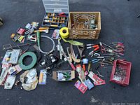 Overview of assortment of 50+ pieces including hand tools, hardware, power tool accessories, wires, trays, and cases spread out on surface.