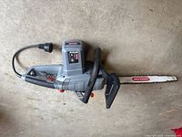 Oregon corded electric chainsaw with 18 inch bar and power cord, gray body with black handle and guard