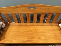 Front view of wooden bench seat and backrest with vertical slats and handle.