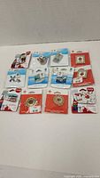 Overview of all 10 pins in packaging showing various designs including Coca-Cola and Olympic logos