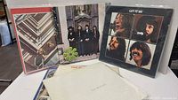 Overview of Beatles vinyl record covers showing Abbey Road and Let It Be album covers, along with the White Album in protective plastic