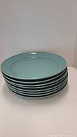 Stack of 7 round blue ceramic dinner plates with smooth glaze finish.
