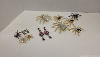 Full lot showing various spider-themed brooches and earrings on a white background