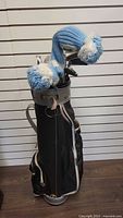 Full view of golf bag with clubs and yarn headcovers in blue and white