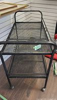 Full view of the black heavy duty metal cart showing mesh shelves, tubular metal frame and caster wheels.