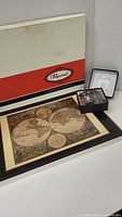 Photo showing Papyrus branded box for the placemat, world map placemat, and boxed set of coasters on a white surface.