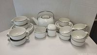 Complete tea set displayed on white background showing teapot, creamer, sugar bowl, cups, and plates with silver trim.
